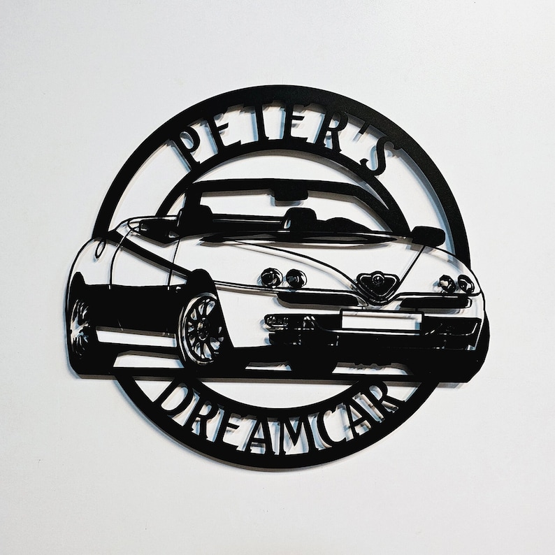 May include: Black metal silhouette of a convertible car with the words "Peter's Dreamcar" around it.