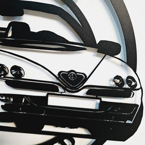 May include: Black and white silhouette of an Alfa Romeo sports car. The car is shown from the front, with the headlights, grille, and hood visible.