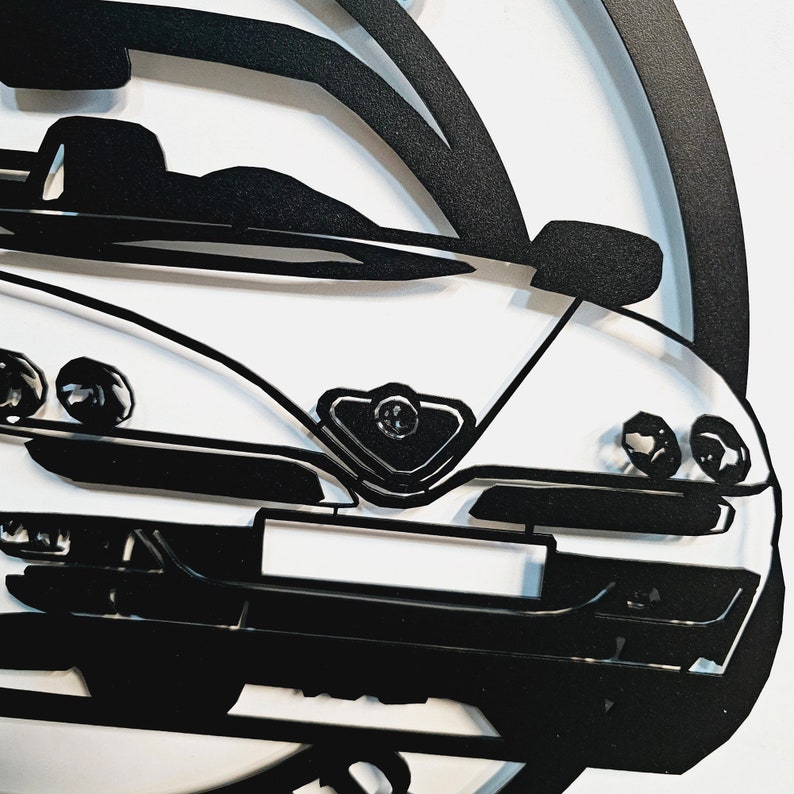 May include: Black and white silhouette of an Alfa Romeo sports car. The car is shown from the front, with the headlights, grille, and hood visible.