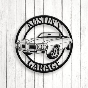 May include: Black metal sign with a circle design. The sign says "Austin's Garage" with a vintage car inside the circle.