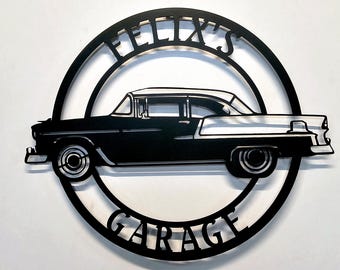 May include: Black metal sign with a classic car silhouette inside a circular frame. The words "FELIX'S" and "GARAGE" are cut out above and below the car. The sign is designed for wall mounting, suitable for a garage or car enthusiast.