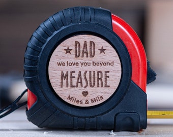 May include: A red and black tape measure with a wooden plaque that reads "Dad we love you beyond measure" with a heart and the names "Miles & Mila".