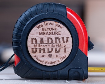May include: A red and black tape measure with a wooden insert that reads "We love you beyond measure Daddy Miles♥Mila♥Milo Happy Father's Day".