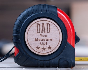 May include: A red and black tape measure with a wooden plaque that reads "Dad You Measure Up!" with three stars.