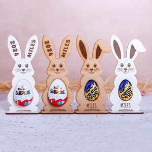 Personalised Easter Egg Holder made from 3mm wood or 4mm Beech Veneered Wood, Egg holder has a cut out to fit Kinder Surprise Egg and Cadbury Egg Creme, Name engraved in front of the wooden Easter bunny standing with a base.