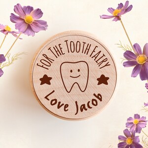 Puede incluir: Una caja de madera para el hada de los dientes con un gráfico de un diente sonriente y el texto "For the Tooth Fairy Love Jacob" grabado en la tapa.