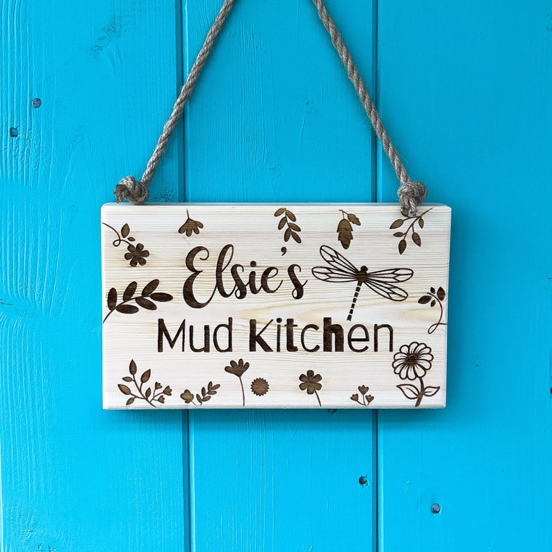 Mud Kitchen Sign With Dragon Fly and Floral Design Frame Around the Name and Mud Kitchen Text