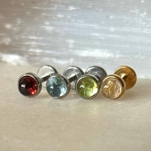 Könnte beinhalten: Fünf Ohrringe mit verschiedenen Edelsteinen in unterschiedlichen Farben. Die Ohrringe sind aus Chirurgenstahl gefertigt und haben verschiedene Edelsteine, darunter rot, blau, grün und gelb.