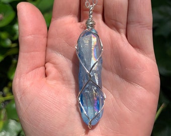 Puede incluir: Un collar de cadena de plata con un colgante de cristal azul envuelto en alambre de plata.