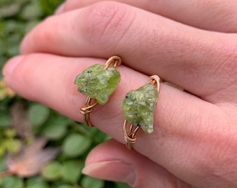 May include: Two rings with green peridot stones wrapped in gold wire.
