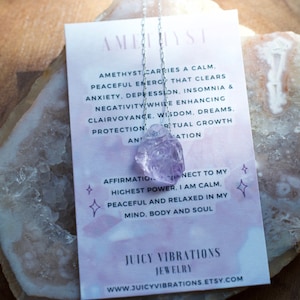 May include: Amethyst crystal necklace with a silver chain. The necklace is displayed on a white card with text about the healing properties of amethyst. The text reads: "Amethyst carries a calm, peaceful energy that clears anxiety, depression, insomnia & negativity while enhancing clairvoyance, wisdom, dreams, protection and spiritual growth and affirmation. Connect to my highest power. I am calm, peaceful and relaxed in my mind, body and soul. Juicy Vibrations Jewellery www.juicyvibrations.etsy.com"