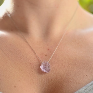 May include: A silver chain necklace with a light purple crystal pendant.