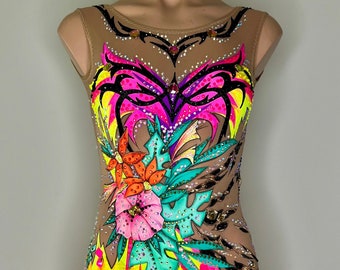 May include: A vibrant, decorated leotard for rhythmic gymnastics. The nude-colored base is adorned with a colorful floral design in shades of pink, orange, yellow, and turquoise. Black accents and rhinestones add sparkle. The leotard is displayed on a mannequin.