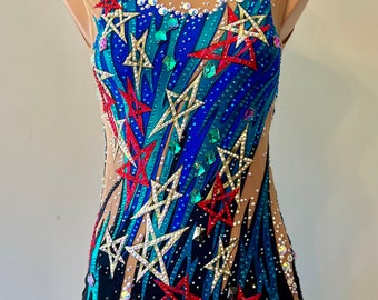 May include: A black leotard with a blue, teal, and red star pattern. The leotard is decorated with rhinestones and has a scoop neckline.