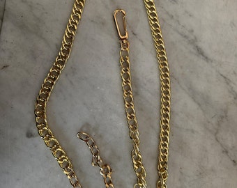 May include: A gold chain with a lobster clasp. The chain is made of thick, linked metal.