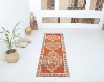 May include: A long, rectangular rug with a traditional Persian design. The rug has a red background with intricate patterns in shades of orange, pink, and cream.