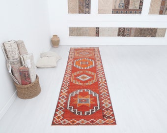 May include: A red, orange, and white patterned runner rug with geometric designs. The rug has a traditional, tribal look.