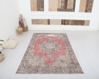 May include: A vintage rug with a faded red center and intricate floral patterns in shades of blue, beige, and cream. The rug has a distressed look and is perfect for adding a touch of bohemian style to any room.
