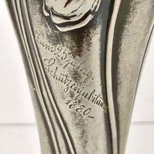 K&ouml;nnte beinhalten: Eine silberne Vase mit Tulpenmotiv und der Inschrift "Zum 25. jahrigen Schutztagjubil&auml;um 1880".