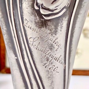 K&ouml;nnte beinhalten: Eine silberne Metallvase mit einem Tulpenmotiv und der Inschrift "Zum 25 j&auml;hrig Sch&uuml;tzenjubil&auml;um 1880".