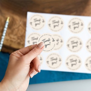 May include: A sheet of round, cream-colored stickers with the text "Thank you!" in black script. The stickers are surrounded by a black circle with the text "Hand made with love and made with love" in black.