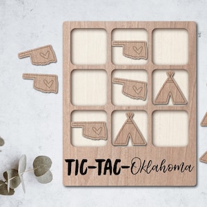 May include: Wooden tic-tac-toe game with Oklahoma state outlines and teepee shapes. The game board is made of light brown wood and has the words "TIC-TAC-Oklahoma" printed on the bottom.