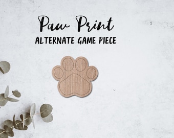 May include: Wooden paw print game piece. The piece is shaped like a paw print with four toes and a pad. The piece is light brown in color.
