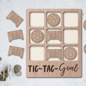 May include: Wooden tic-tac-toe game with a football theme. The game board has nine squares and the pieces are footballs and goal posts. The game board is labelled "TIC-TAC-Goal".