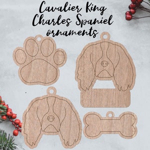 May include: Four wooden ornaments featuring a Cavalier King Charles Spaniel dog, a paw print, a bone, and a blank space for personalization. The ornaments are made of light brown wood with a wood grain texture.