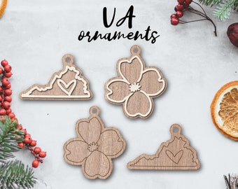 May include: Four wooden ornaments featuring the state of Virginia and a dogwood flower. The ornaments are painted in a light brown color and have a white outline. The text "VA ornaments" is written above the ornaments.