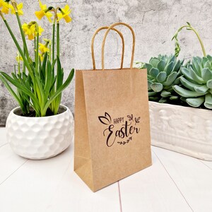 Sac-cadeau kraft Joyeuses Pâques. Sac cadeau chasse aux œufs estampé à la main. Sac de fête avec oreilles de lapin/lapin avec poignées torsadées en papier. Éco minimaliste