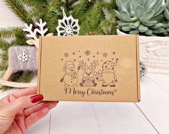 May include: A brown cardboard box with a Christmas-themed design. The box features a snowman, reindeer, and gnome holding gifts. The text "Merry Christmas" is printed on the box.