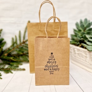 Nous vous souhaitons un joyeux Noël et une bonne année - Sac cadeau de fête en papier kraft. Pochettes cadeaux uniques pour les fêtes de fin d'année avec timbre sapin de Noël