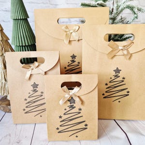 May include: Several kraft paper gift bags of different sizes, each featuring a black Christmas tree design and a gold ribbon bow. The bags have a die-cut handle for carrying, ideal for festive gifting.