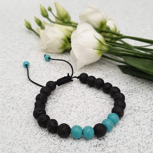 May include: A black lava rock and turquoise beaded bracelet with a black cord closure.