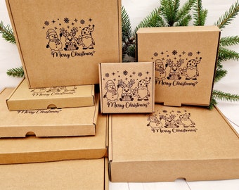 Puede incluir: Un conjunto de seis cajas de cartón marrón con temática navideña. Cada caja tiene un tamaño diferente y presenta una ilustración en blanco y negro de un muñeco de nieve, un reno y un gnomo con el texto "Feliz Navidad".