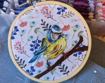 Blaumeise ruhend auf einem Zweig handgestickter Stickrahmen