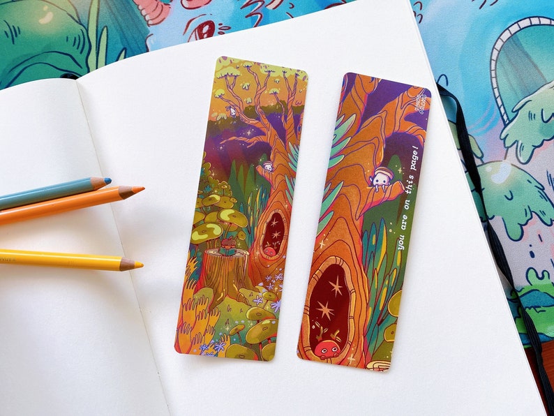 May include: Two colorful bookmarks with illustrations of a tree and a forest scene. The text on one bookmark reads "You are on this page!"