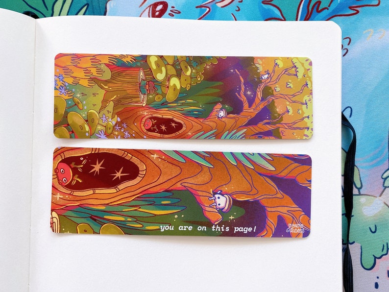 May include: Two colorful bookmarks with a whimsical forest scene. The top bookmark features a large tree with glowing mushrooms and the text "you are on this page!" The bottom bookmark shows a close-up of the tree trunk with a small creature peeking out.