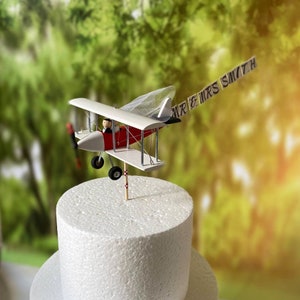 Airplane Wedding Cake Topper with Custom banner Mr. & Mrs. Cute unique honeymoon figurines at the helm of the plane. Fiance Pilot and Bride