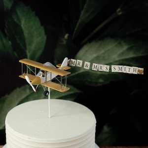 Gold Airplane Wedding Cake Topper with Custom banner Mr. & Mrs. Marriage cute unique honeymoon figurines at the helm of the plane.