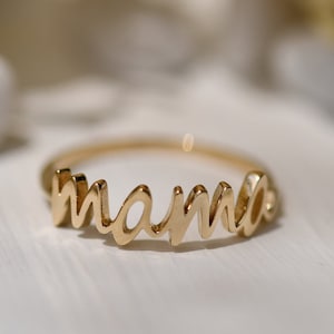 May include: A gold ring with the word "mama" spelled out in cursive.