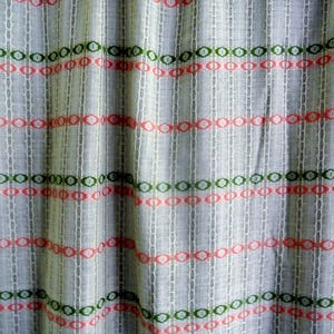 Puede incluir: Primer plano de una cortina transparente con un patrón repetitivo de círculos verdes y coral y rayas verticales. La cortina tiene un fondo beige claro y está ligeramente arrugada.