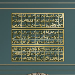 May include: Three gold framed pieces of Islamic calligraphy hang on a teal wall above a teal and blue velvet sofa. The sofa is in a room with gold trim and a gold coffee table.