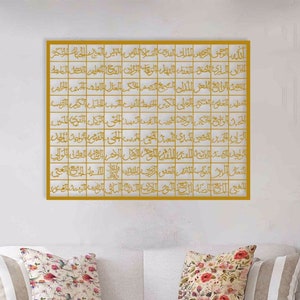 May include: A gold framed square wall art piece with Arabic calligraphy in a grid pattern. The calligraphy is in a gold color.