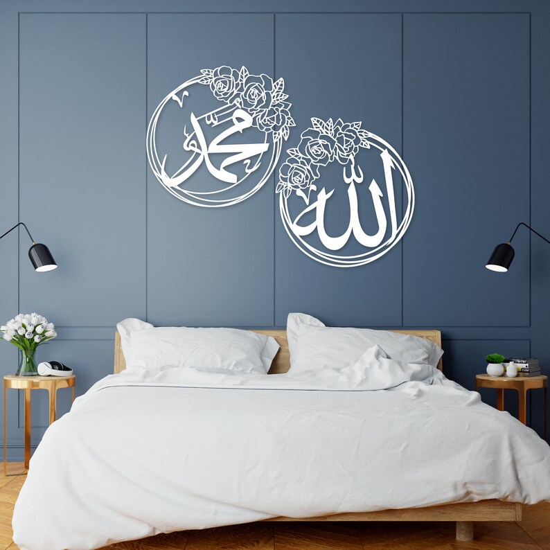 K&ouml;nnte beinhalten: Zwei wei&szlig;e Holz-Wanddekorationen mit floralen Designs. Das linke St&uuml;ck zeigt das arabische Wort f&uuml;r "Muhammad" und das rechte St&uuml;ck zeigt das arabische Wort f&uuml;r "Allah".