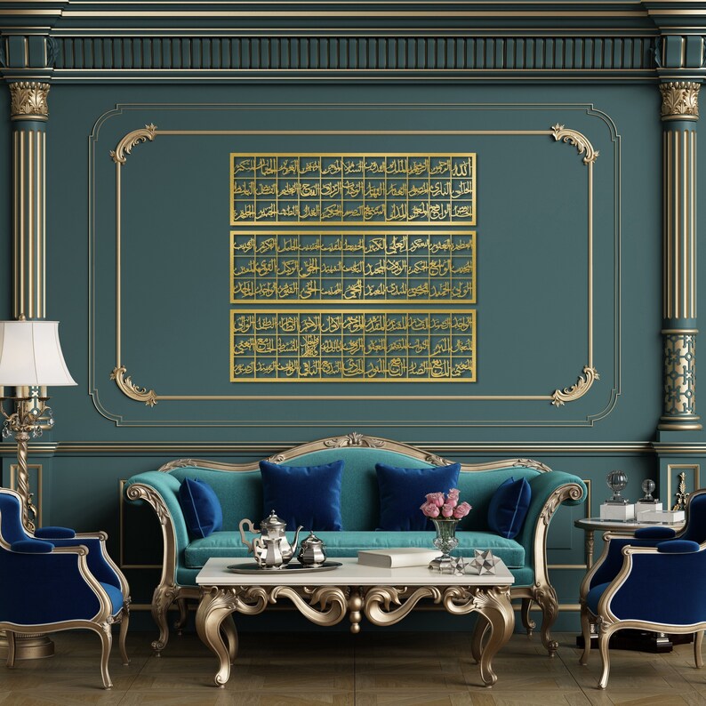 May include: Three gold framed pieces of Islamic calligraphy hang on a teal wall above a teal and blue velvet sofa. The sofa is in a room with gold trim and a gold coffee table.