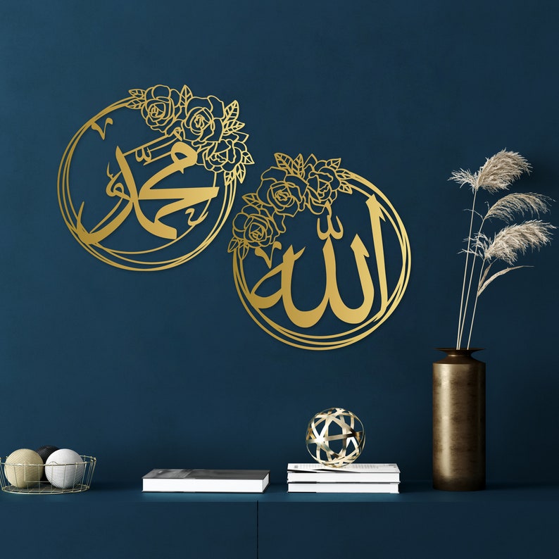 K&ouml;nnte beinhalten: Zwei goldene Wanddekorationen aus Metall mit floralen Designs. Das linke St&uuml;ck zeigt das arabische Wort f&uuml;r "Muhammad" und das rechte St&uuml;ck zeigt das arabische Wort f&uuml;r "Allah".