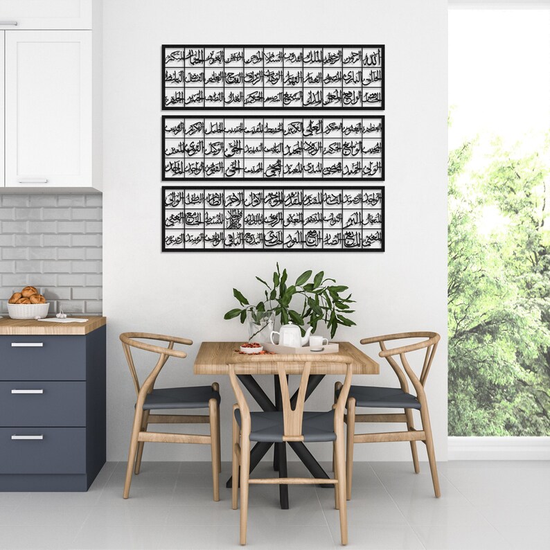 May include: Three black framed pieces of Islamic calligraphy art hang on a white wall above a wooden table with four chairs. The calligraphy is in Arabic script.