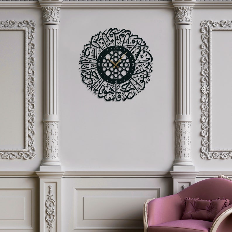 May include: A black metal wall clock with Arabic calligraphy around the face. The clock has gold hands and a white face with black numbers.